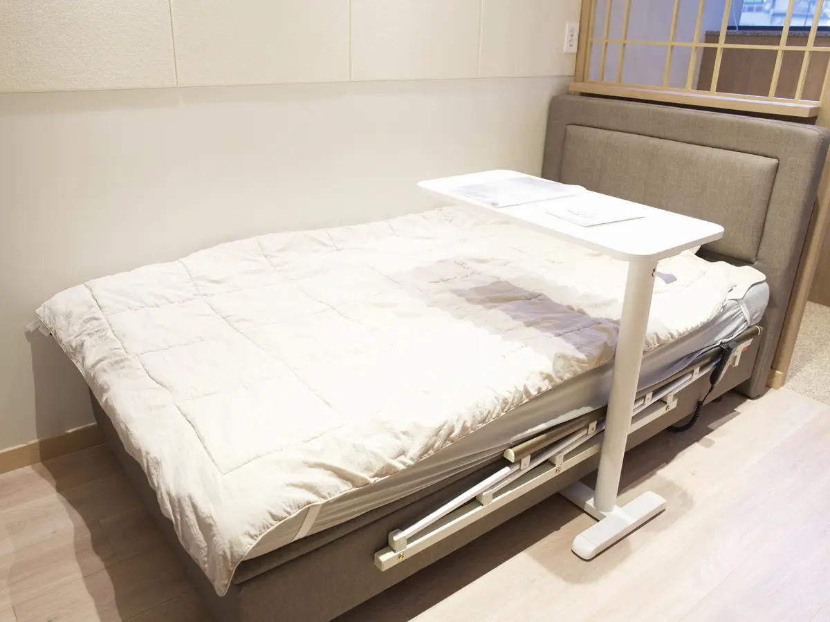 전동 침대와 침대용 테이블이 놓인 입원실